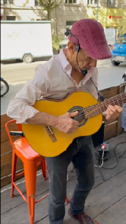 Pablo, casquette rouge et guitare, assis sur une chaise orange